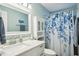 Bright bathroom with a floral shower curtain, white vanity, and a large mirror at 2467 Finlandia Ln # 43, Clearwater, FL 33763