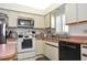 Well-lit kitchen features modern appliances, tile flooring, and ample storage with light countertops and white cabinetry at 4078 Salem Square Pkwy, Palm Harbor, FL 34685