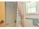 Shower over tub in the bathroom, complete with neutral tile, grab bar and shuttered window at 4078 Salem Square Pkwy, Palm Harbor, FL 34685