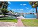 Beautiful backyard featuring a boat dock, lush lawn, mature palm trees, and stunning water views at 6410 3Rd Palm Pt, St Pete Beach, FL 33706