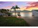 Charming one-story home featuring lush landscaping, a brick walkway, and a two-car garage under a vibrant sunset at 6410 3Rd Palm Pt, St Pete Beach, FL 33706