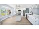 Kitchen with bay window, stainless steel appliances, kitchen island, white cabinets, and modern lighting at 6410 3Rd Palm Pt, St Pete Beach, FL 33706