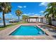 Inviting backyard oasis with a sparkling pool, covered patio, waterfront views, and lush landscaping at 6410 3Rd Palm Pt, St Pete Beach, FL 33706