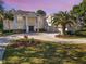 Elegant white home with landscaping, circular drive and a sunset-colored sky at 6413 Maclaurin Dr, Tampa, FL 33647