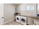 Well-lit laundry room featuring wood-look tile flooring, granite counters, cabinets, sink, and washer and dryer at 6413 Maclaurin Dr, Tampa, FL 33647