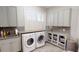 Bright laundry room with granite countertops, cabinets, sink, window, and a washer and dryer at 6413 Maclaurin Dr, Tampa, FL 33647