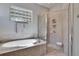 Bright bathroom features a soaking tub and a glass enclosed shower with seat at 830 Regal Manor Way # 1, Sun City Center, FL 33573