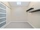 Walk-in closet featuring a skylight, floating shelves, modern sliding door, and neutral color palette at 12605 Catamaran Pl, Tampa, FL 33618