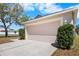 Attached garage with a light-colored door, surrounded by manicured greenery, and ample parking on the driveway at 12802 Lake Vista Dr, Gibsonton, FL 33534
