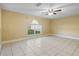 Bright, airy living room with tile flooring, a ceiling fan, and a large window offering backyard views at 12802 Lake Vista Dr, Gibsonton, FL 33534