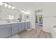 Bright bathroom featuring double sinks, modern fixtures, with wood-look flooring and a bedroom view at 2944 Billingham Dr, Land O Lakes, FL 34639