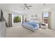 Light-filled main bedroom with a ceiling fan, neutral carpet, and a large window offering a pleasant view of trees at 2944 Billingham Dr, Land O Lakes, FL 34639