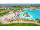Aerial view of the community beach with a vibrant lagoon, palm trees, volleyball court, and sandy areas at 30753 Penny Surf Loop, Wesley Chapel, FL 33545