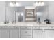 Bright bathroom with double sinks, white cabinets, quartz countertop, and a large mirror reflecting the walk-in shower at 318 Blackrock Ln, Apollo Beach, FL 33572