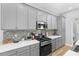 Well-equipped kitchen featuring gray cabinets, stainless steel appliances, mosaic backsplash, and ample counter space at 318 Blackrock Ln, Apollo Beach, FL 33572