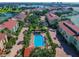Drone shot of neighborhood highlighting a pool and cabana, mature trees, and residential buildings with red tile roofs at 406 Sandy Hook Rd, Treasure Island, FL 33706