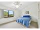 Bright bedroom features a ceiling fan, carpet, and window with a view of tropical palm trees at 406 Sandy Hook Rd, Treasure Island, FL 33706