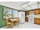 Kitchen featuring wood cabinets, white appliances, tile floor, and breakfast nook with window views at 406 Sandy Hook Rd, Treasure Island, FL 33706