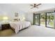 Bright main bedroom featuring a ceiling fan, carpeted floors, and sliding doors to a balcony with beautiful views at 406 Sandy Hook Rd, Treasure Island, FL 33706