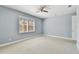 Bright bedroom with neutral carpet, light blue walls and a ceiling fan and window with plantation shutters at 5014 W Lancaster St, Tampa, FL 33616