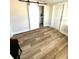 Bedroom featuring wood-look floors, barn door leading to bath, and a bright interior at 5123 5Th St, Zephyrhills, FL 33542