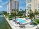 Exterior view of a community pool surrounded by palm trees and lounge chairs at 5200 Brittany S Dr # 1503, St Petersburg, FL 33715