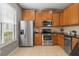 Well-lit kitchen featuring stainless steel appliances, wood cabinetry, and neutral tile flooring at 555 52Nd N Ave, St Petersburg, FL 33703
