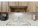 Close-up of kitchen sink with stainless steel faucet and upper wood cabinets at 7717 Radcliffe Cir, Port Richey, FL 34668