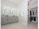 Bathroom with double sinks, a large mirror, granite countertop and access to a walk-in closet at 8261 Ivy Stark Blvd, Wesley Chapel, FL 33545