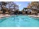 Image of a pristine swimming pool with crystal-clear water, shaded by mature oak trees, with an adjacent building at 865 Virginia Ct # 106, Dunedin, FL 34698