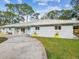 Charming home with a curved driveway, well-maintained lawn, and vibrant yellow planters at 8693 15Th N St, St Petersburg, FL 33702
