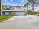 View of home showing the two-car garage and driveway, surrounded by mature trees and well maintained lawn at 8693 15Th N St, St Petersburg, FL 33702