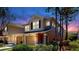 Well-lit two-story townhome featuring an attached garage and lush landscaping at dusk at 10209 Spanish Breeze Ct, Riverview, FL 33578