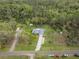 Aerial view of house with long driveway, camper, storage building, and bordering trees at 1126 Oxbow Rd, Wimauma, FL 33598