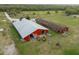 Aerial view of a red barn with a silver roof amid expansive fields and paddocks at 1126 Oxbow Rd, Wimauma, FL 33598