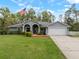 Charming single-story home featuring a well-manicured lawn and an inviting arched entryway with American flag at 1126 Oxbow Rd, Wimauma, FL 33598