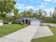 Single-story home with a spacious driveway, manicured lawn, and white picket fence, perfect for suburban living at 1126 Oxbow Rd, Wimauma, FL 33598