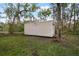 Backyard view of an outdoor outbuilding storage shed on a grass lot surrounded by trees at 1126 Oxbow Rd, Wimauma, FL 33598
