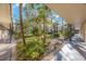 Exterior view of a unit's walkway with lush landscaping with mature trees and various plants in the courtyard at 11485 Oakhurst Rd # 111, Largo, FL 33774
