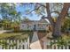 Charming home featuring mature trees, a well-manicured lawn, and a classic white picket fence at 1205 13Th N St, St Petersburg, FL 33705