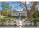 Charming home featuring mature trees, a well-manicured lawn, and a classic white picket fence at 1205 13Th N St, St Petersburg, FL 33705