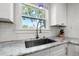 Close-up on modern kitchen sink with granite countertops and white cabinets beneath bright window at 1205 13Th N St, St Petersburg, FL 33705