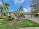 Landscaped Florida home with a three-car garage, tropical landscaping, and a red front door at 1403 Crooked Stick Dr, Valrico, FL 33596