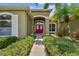 Inviting entrance of Florida home with a red double door, lush landscaping, and mature palms at 1403 Crooked Stick Dr, Valrico, FL 33596