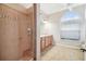Bathroom with tiled shower and glass door, vanity with light wood cabinets, and arched window at 23523 Gracewood Cir, Land O Lakes, FL 34639