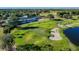 Scenic aerial view of the golf course with rolling greens, a sand bunker, and a nearby pond at 23523 Gracewood Cir, Land O Lakes, FL 34639