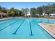 An inviting large community pool with clearly marked lanes, surrounded by trees, lounge chairs and shaded areas at 248 Argyll Dr, Spring Hill, FL 34609