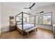 Serene bedroom with a four-poster bed, hardwood floors, ample natural light, and tropical-themed decor at 3006 Christophers Watch Ln, Ruskin, FL 33570