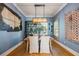 Stylish dining room with a modern light fixture, unique artwork, and a rustic wooden table at 3006 Christophers Watch Ln, Ruskin, FL 33570