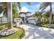 Beautiful two-story white home with a brick driveway, lush tropical landscaping and palm trees at 3006 Christophers Watch Ln, Ruskin, FL 33570